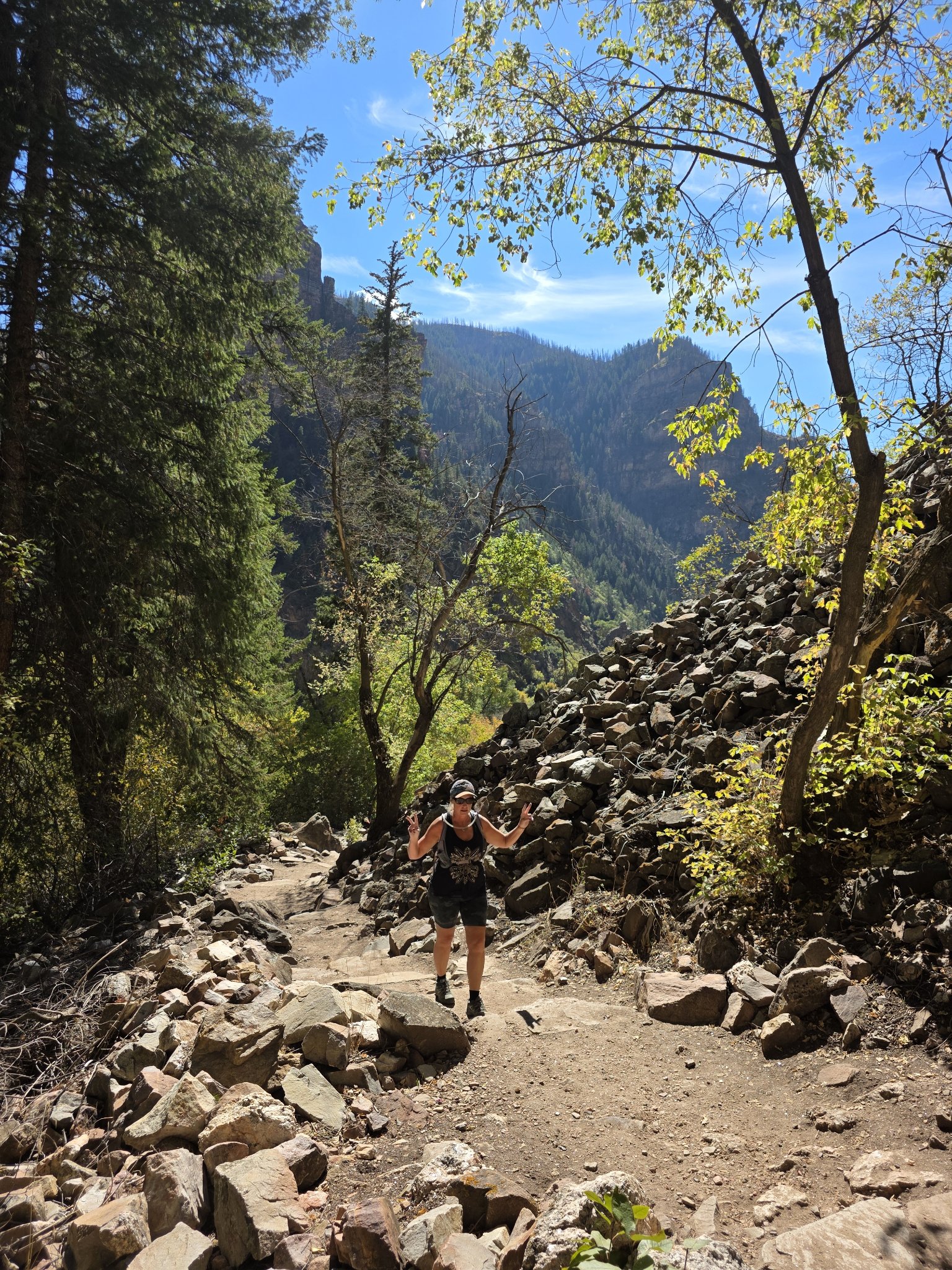 Michelle flashing peace signs on the rocky trail with the canyon rising behind her