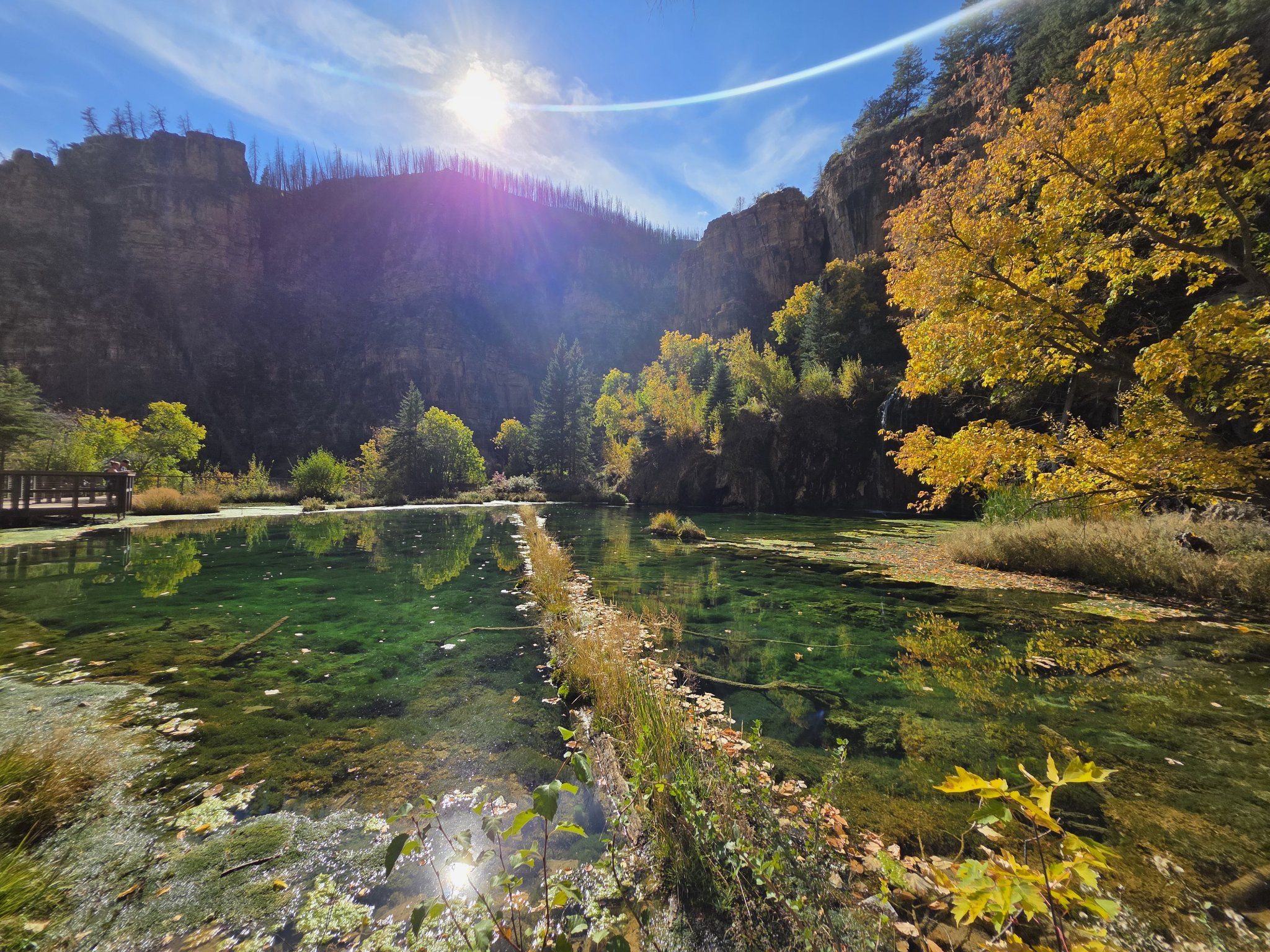 The turquoise waters of Hanging Lake glowing beneath towering canyon walls and golden fall foliage