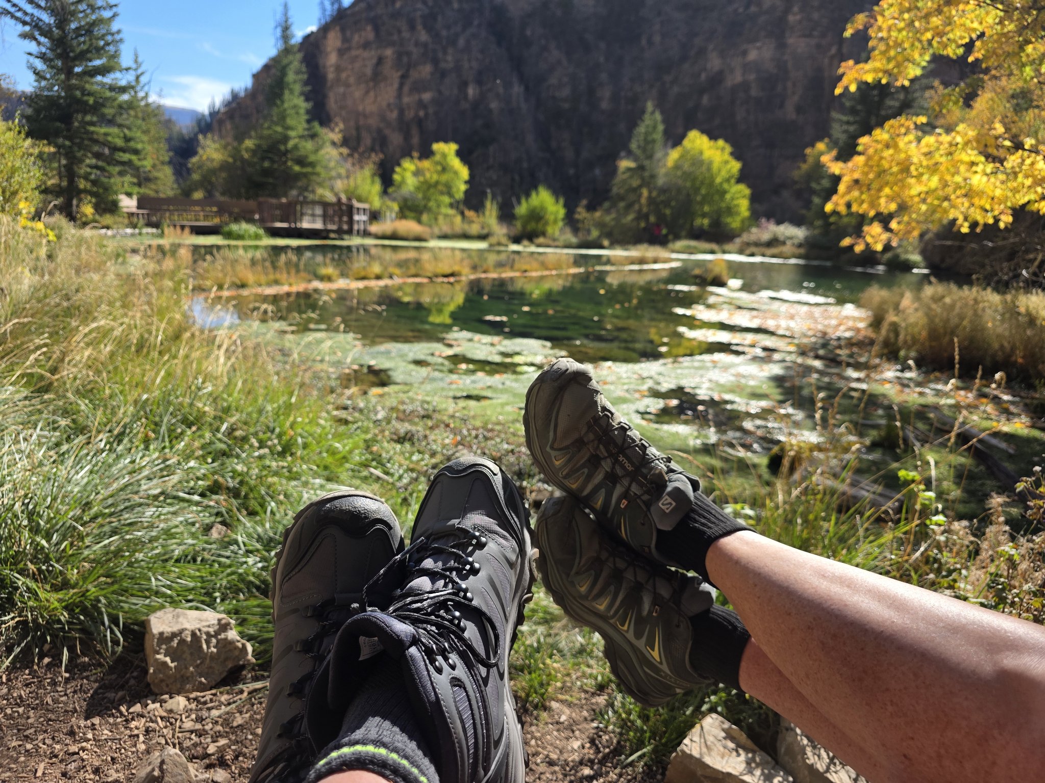Two pairs of hiking boots kicked up at the edge of Hanging Lake — the well-earned rest