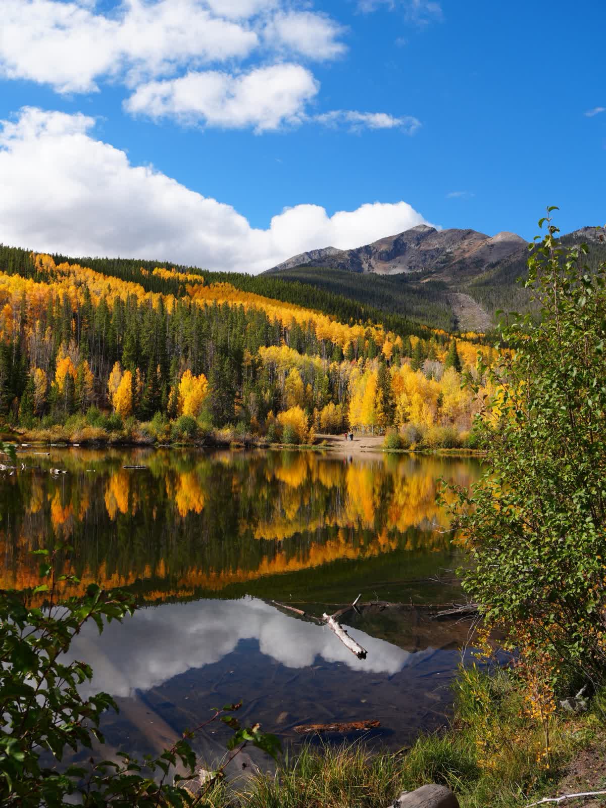 Wide view of Rainbow Lake with golden aspen hillsides and mountain peaks, early October